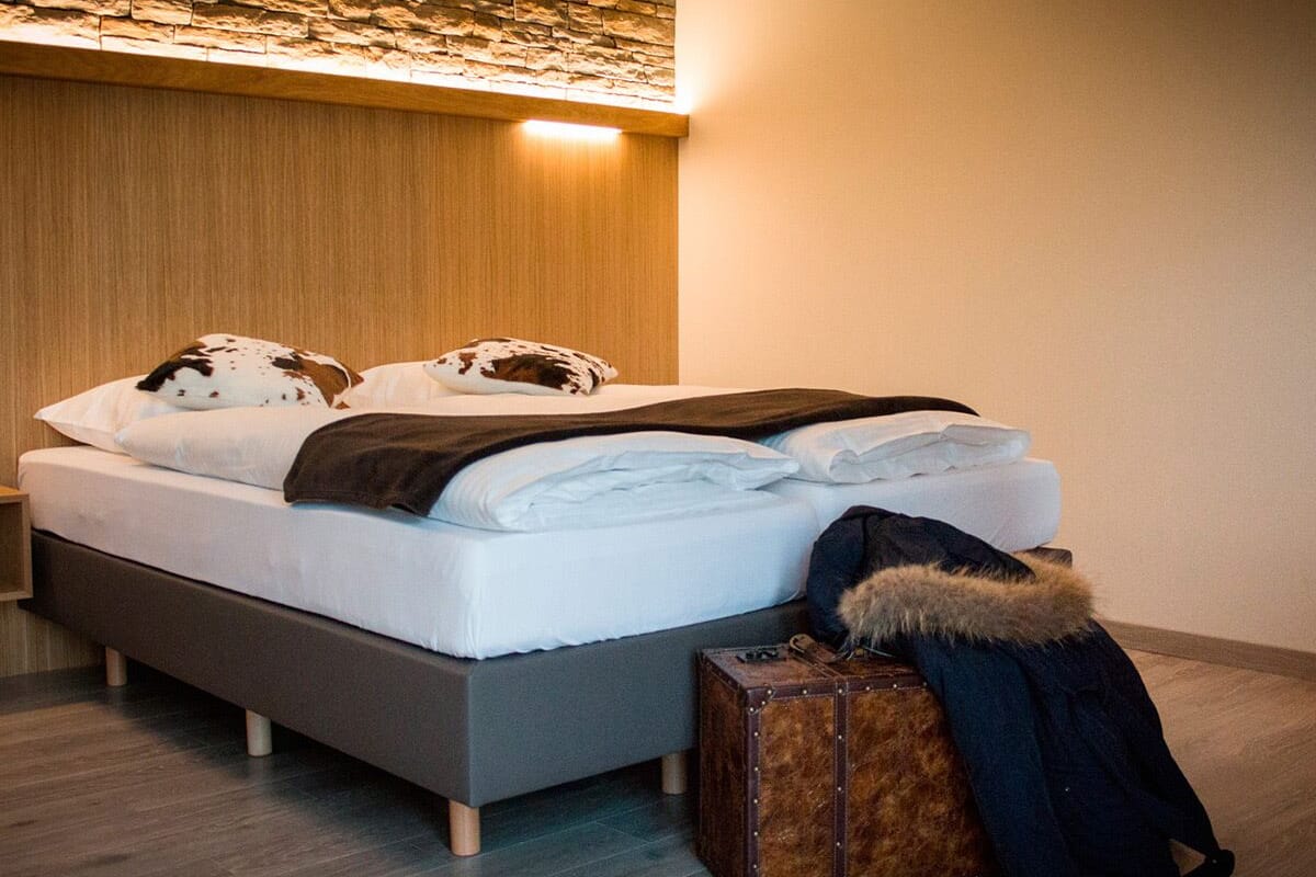 Un dormitorio moderno con una cama, una maleta y una chaqueta de piel en el suelo.