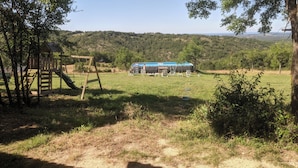 Uma casinha de madeira rústica com um escorrega e uma mesa de piquenique em um campo gramado.