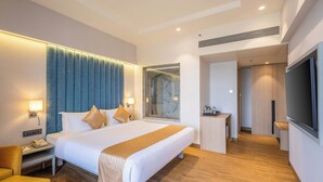 Een moderne hotelkamer met een groot bed, douche, bureau en televisie.