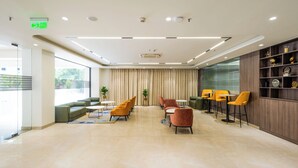 Een moderne lobby met een zithoek, een receptiebalie en een wand met decoratieve objecten.