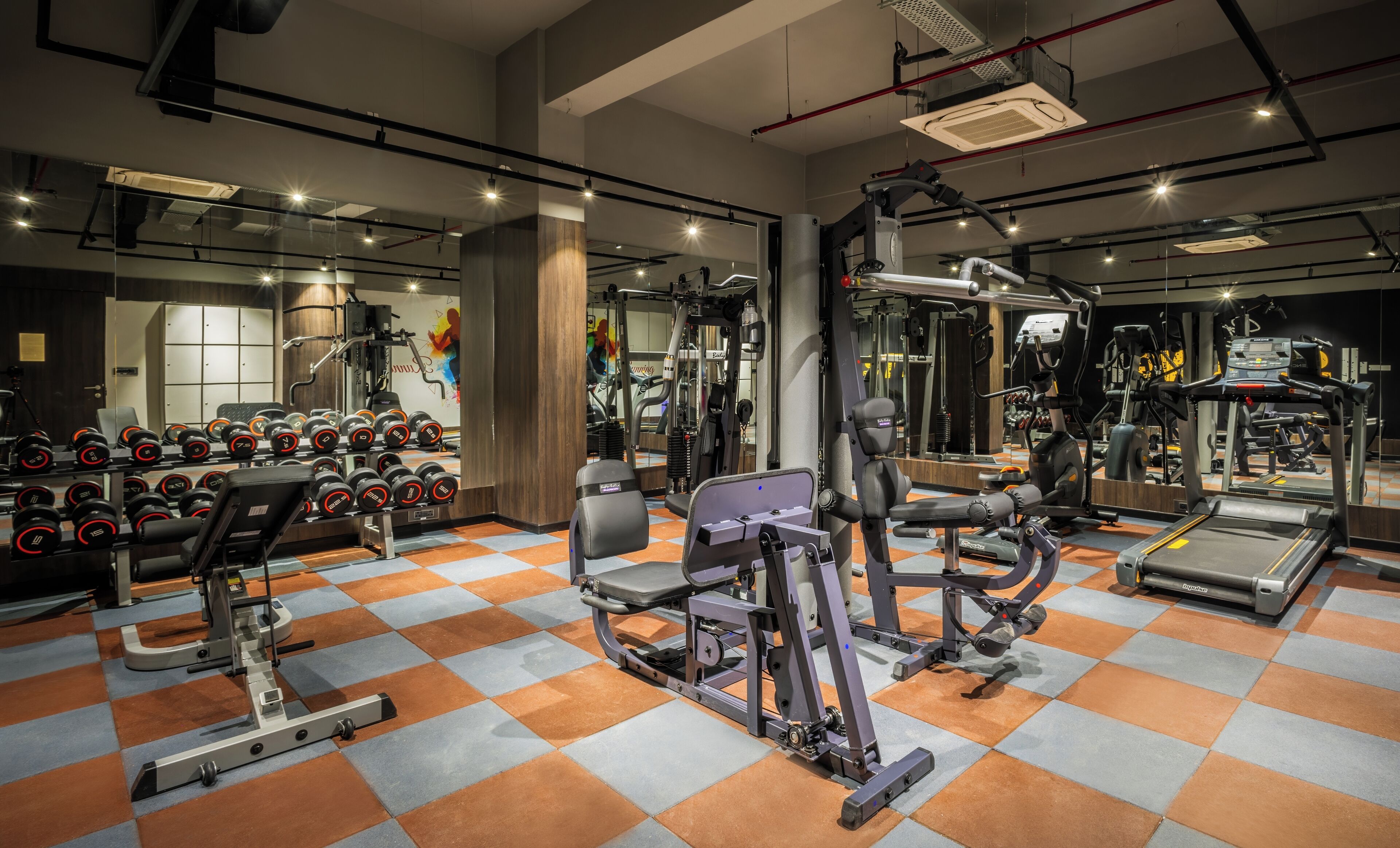 A gym with various exercise equipment, including dumbbells, treadmills, and weight machines.