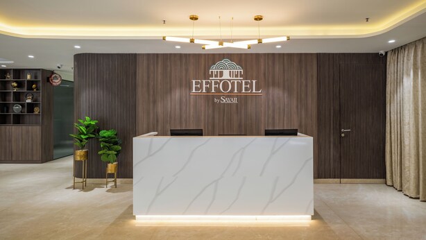 Een modern ontworpen receptiebalie, met een logo erboven, en een houten wandpaneel op de achtergrond.