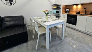 A modern kitchen with white cabinets, a black kettle, and a coffee machine. - Apartament Zielony Przylądek - 365PAM (Ustronie Morskie)