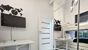 A modern room with a bunk bed, a desk with a computer, a world map clock, and a TV. - Apartament Zielony Przylądek - 365PAM (Ustronie Morskie)