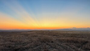 Un paysage vaste et dégagé, avec un ciel clair et des montagnes à l’horizon.