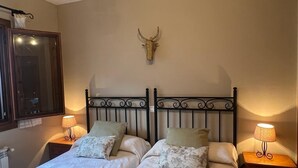 Une chambre avec deux lits, une décoration murale représentant une tête de taureau et des lampes de chevet.