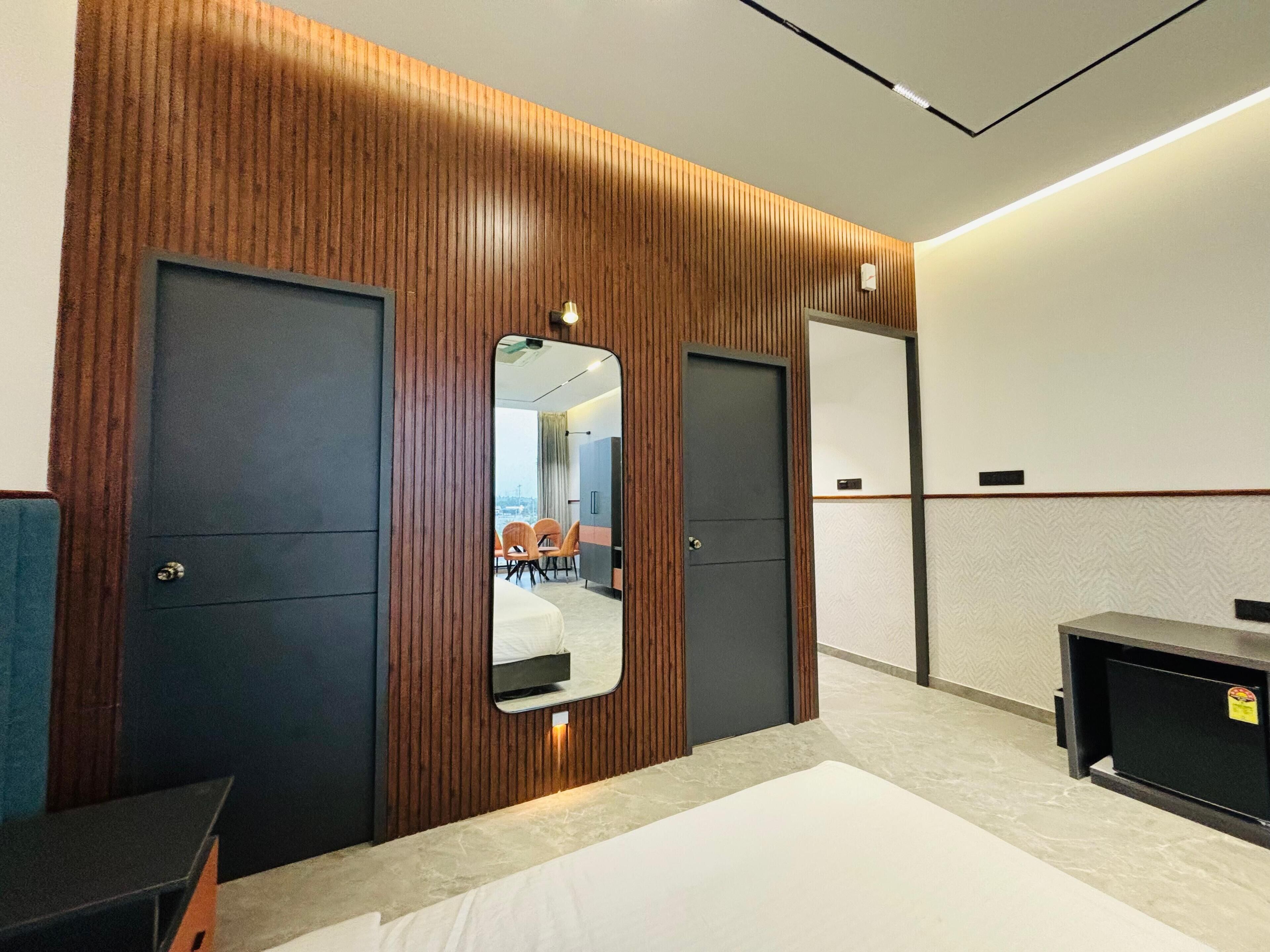 A hotel room with a large bed, two doors, a mirror, and a small desk.