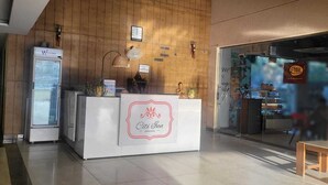 Un espace d’accueil d’hôtel avec un mur en bois, un comptoir de réception, un réfrigérateur et une enseigne de restaurant bien visible.