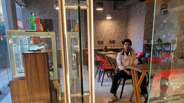 L’intérieur d’un café moderne, avec une cloison en verre, un comptoir en bois et des chaises rouges.