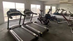 Une salle de sport équipée de tapis de course, de vélos d’appartement et d’un appareil d’aviron.
