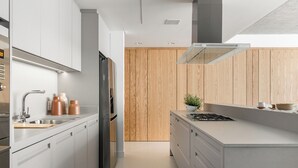 Una cocina moderna con armarios blancos, electrodomésticos de acero inoxidable y una pared de acento de madera.