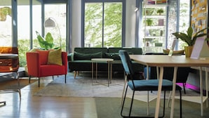 A modern living room with a green sofa, a red armchair, a small table, and a chair. - Sigma Self Check-In Hostel (Zürich)