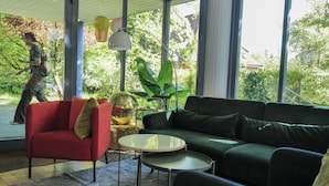 A modern living room with a red armchair, a dark green sofa, and a small round table. - Sigma Self Check-In Hostel (Zürich)