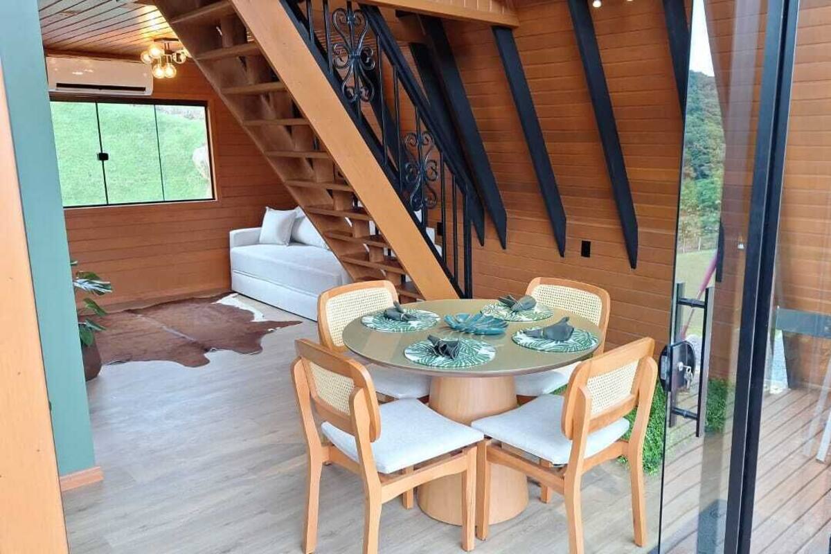 Un coin repas avec une table ronde et six chaises, un escalier et, au fond, un canapé blanc.