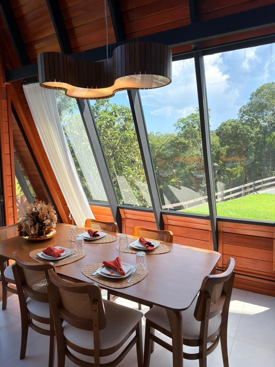 A dining area with a table set for four, large windows, and a view of the outdoors.