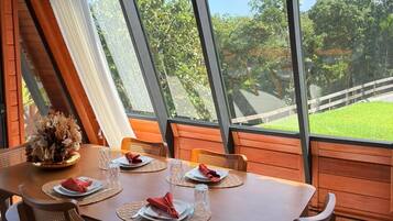 A dining area with a table set for four, large windows, and a view of the outdoors.