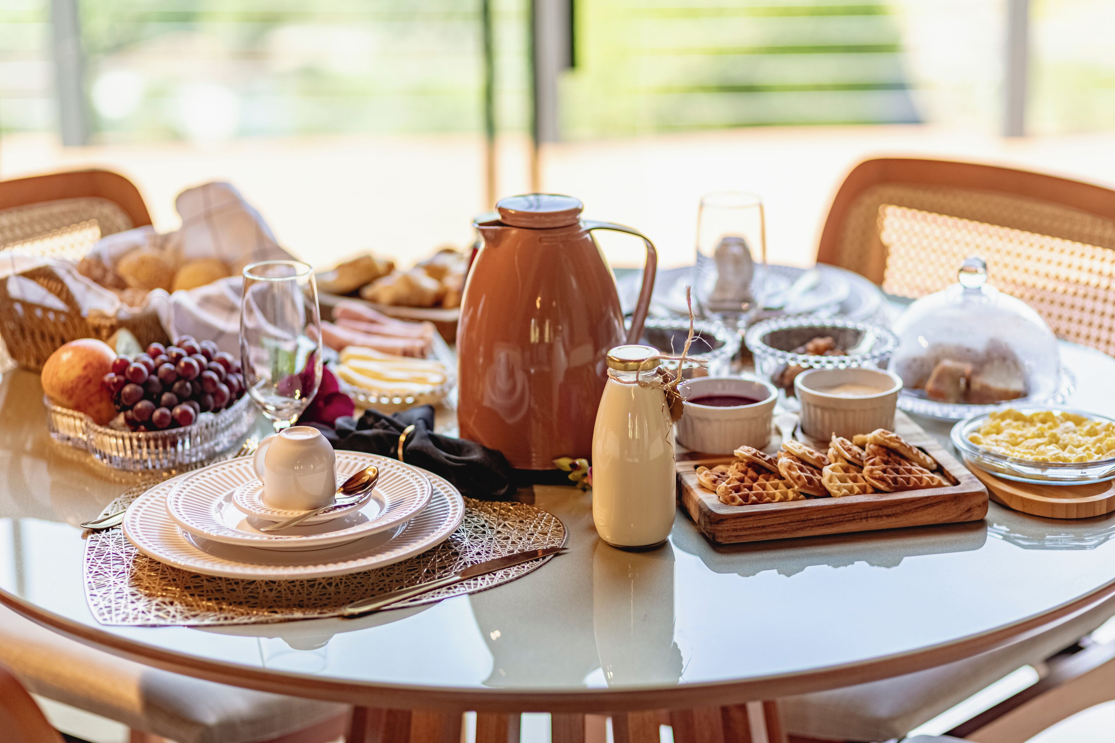 Een ontbijttafel met diverse etenswaren, een koffiepot en een melkkruik.