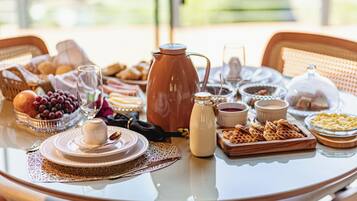 Een ontbijttafel met diverse etenswaren, een koffiepot en een melkkruik.