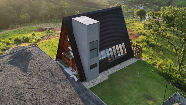 Una casa moderna con techo inclinado, ventanas amplias y un césped cuidado.