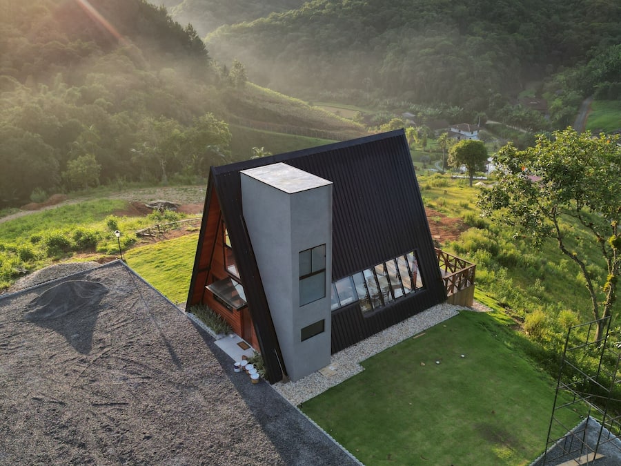 A modern house with a sloped roof, large windows, and a well-maintained lawn.