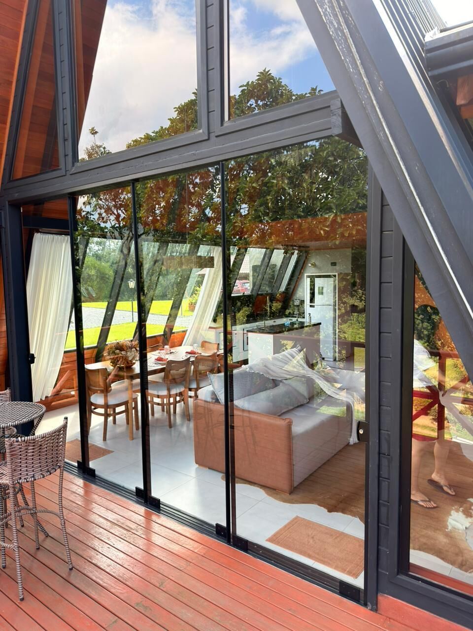A modern interior with a dining area, a sofa, and a kitchen visible through large windows.