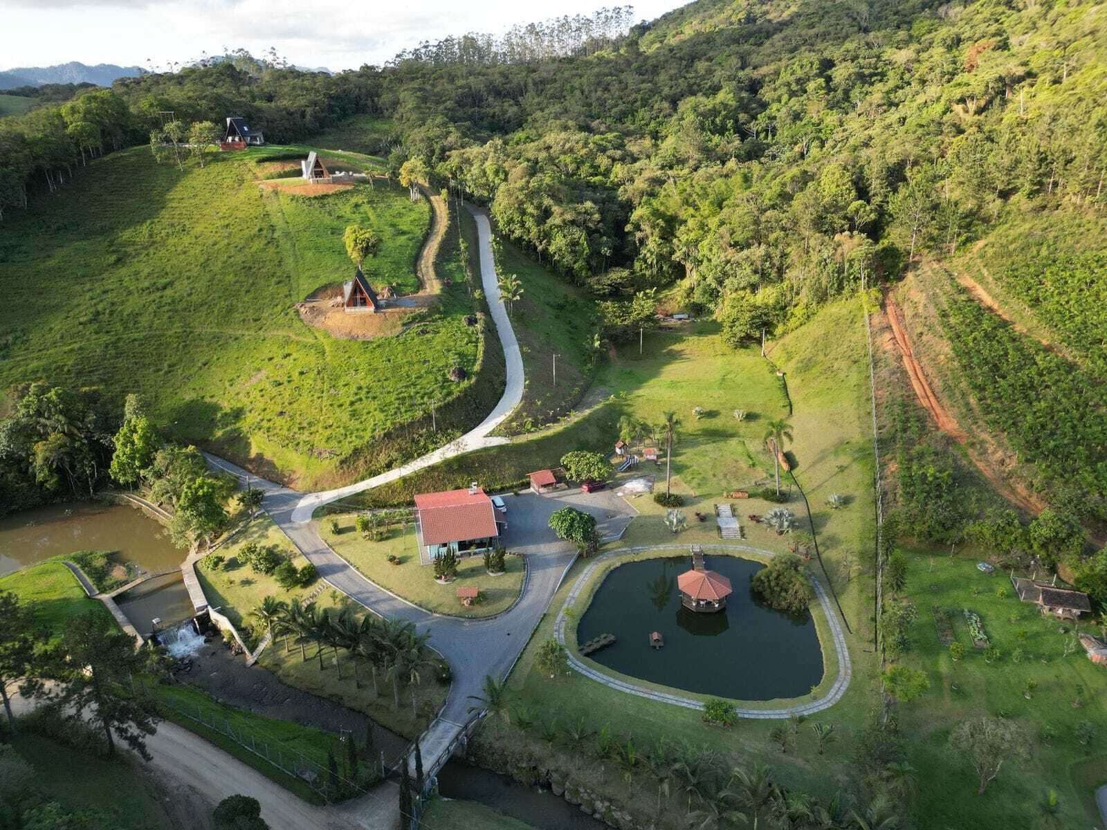 An aerial view of a rural property with a winding road, a small pond, and a few buildings.