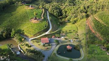 An aerial view of a rural property with a winding road, a small pond, and a few buildings.