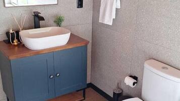 A modern bathroom with a wooden vanity, a white sink, and a toilet.