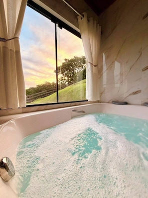 A hot tub with a view of a sunset through a window. - Kleines paradies chalés (Blumenau)