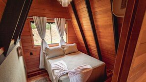 Un dormitorio acogedor con cama, cortinas y techo de madera.