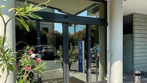 A hotel entrance with a glass door, a doormat with the hotel's name, and a parking area with cars. - Venice Green Residence (Mestre)