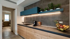 A modern kitchen with a wooden countertop, built-in cabinets, a black sink, and a fruit bowl. - Venice Green Residence (Mestre)