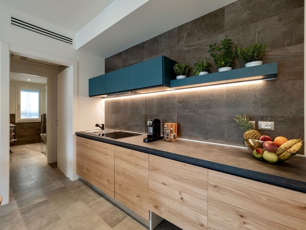 Cocina moderna con encimera de madera, armarios empotrados, un lavabo negro y un frutero.