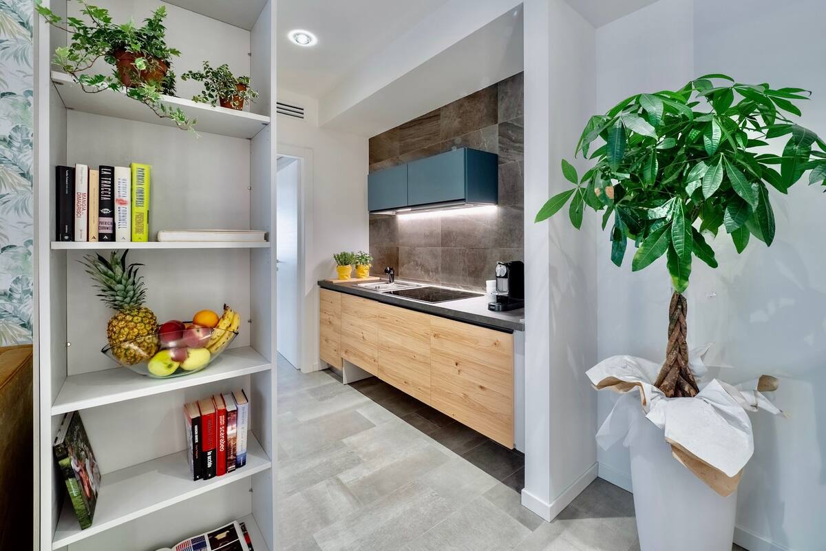 A modern kitchen with wooden cabinets, a built-in stove, and a large potted plant.
