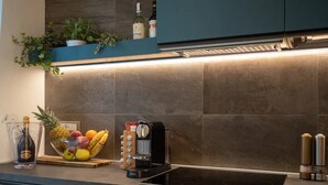 A modern kitchen with a built-in stove, a coffee machine, and a fruit bowl on the counter. - Venice Green Residence (Mestre)