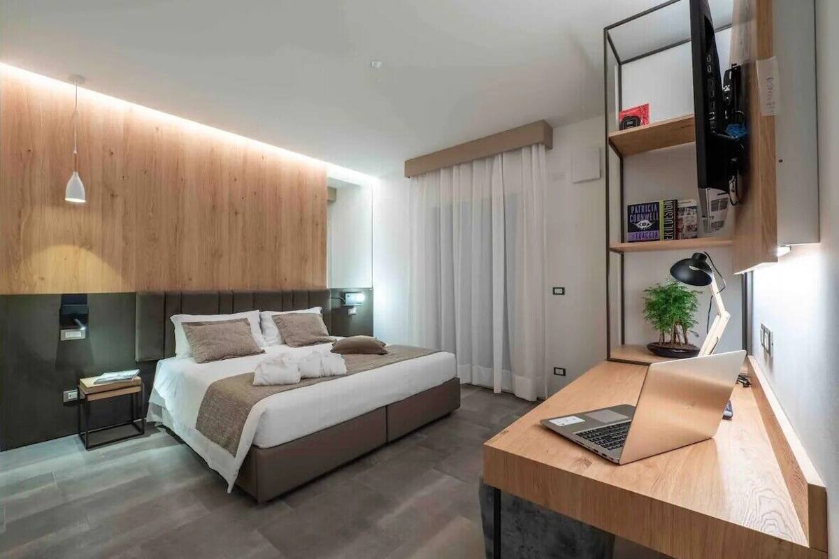 A modern bedroom with a bed, bedside tables, a desk, and a TV.
