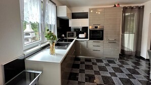 Et moderne køkken med en central ø, rustfrie stålapparater og et skakternet gulv.
