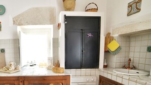 Una cucina con un piano di lavoro bianco, un frigorifero nero, un armadietto in legno e uno schienale piastrellato.