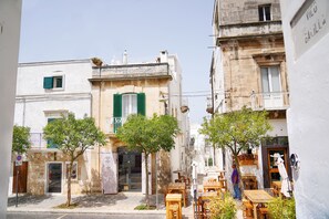 A narrow street with buildings featuring balconies and wooden shutters.