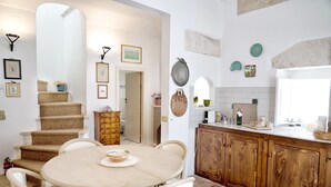 Una cucina con un tavolo rotondo e sedie, mobili impiallacciati in legno e una scala che conduce in un'altra stanza.