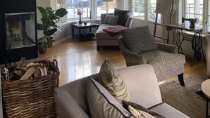 A spacious living room with a fireplace, large windows, and a cozy seating area. - Aarnes House Stryn (Stryn)