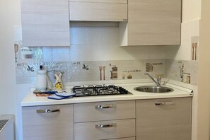 Una cocina con estufa a gas, lavamanos y alacenas.