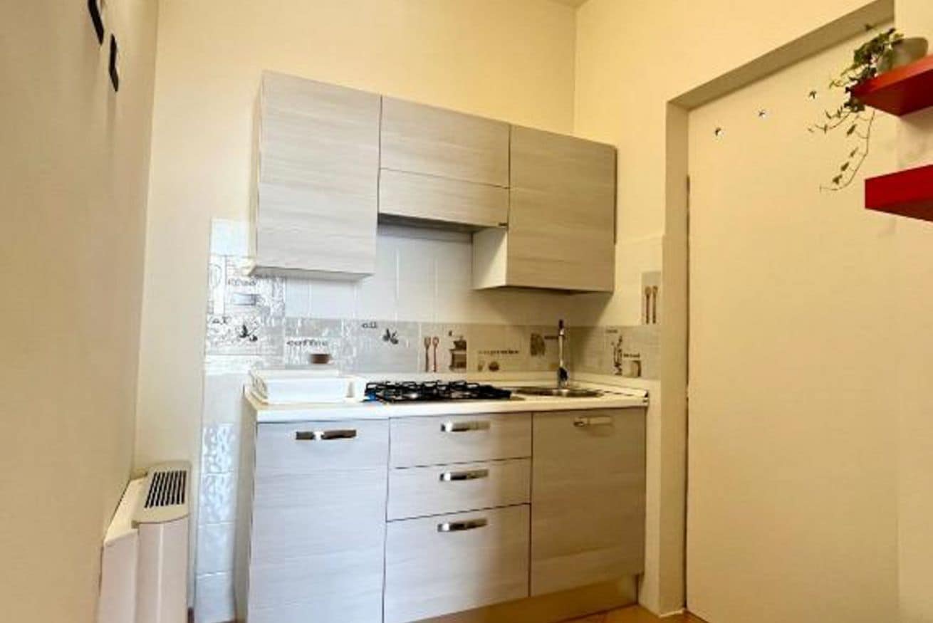 Una cucina compatta con mobili bianchi, un piano cottura a gas e un lavandino.