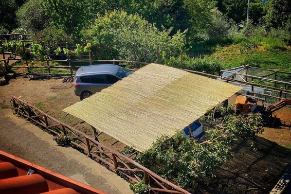A vehicle parked on a dirt surface with a wooden structure in the background.