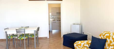 Un espacio habitable compacto con una mesa de comedor, sillas, un sofá y una kitchenette.