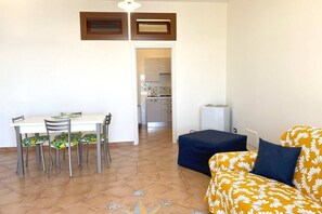 Un espacio habitable compacto con una mesa de comedor, sillas, un sofá y una kitchenette.