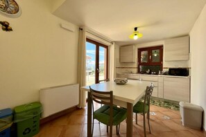 Een kleine keuken met een eettafel, stoelen en uitzicht op buiten.