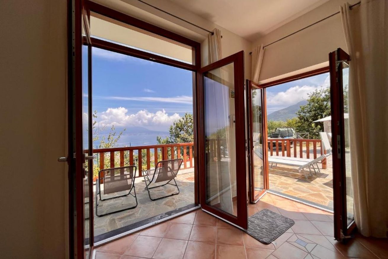 A balcony with a glass door leading to an outdoor seating area with chairs and a table.