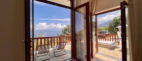 A balcony with a glass door leading to an outdoor seating area with chairs and a table.