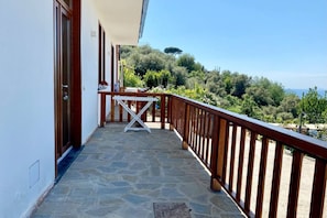 A balcony with a stone floor, wooden railing, and a table with chairs.